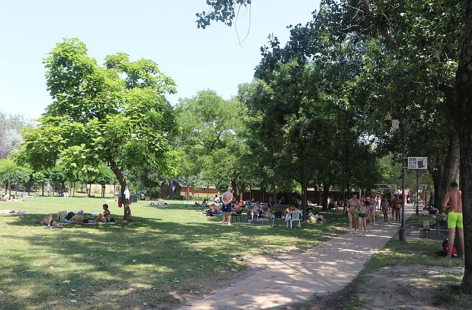People relaxing and seeking shade in a park or beach during a severe heatwave in Serbia.