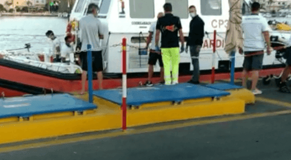 Personnel de la Capitainerie de port près d'un bateau de patrouille à Pantelleria, illustrant la protection de l'environnement marin.