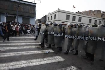 Peruvian police in riot gear facing a crowd of protestors during demonstrations against pension system reforms.