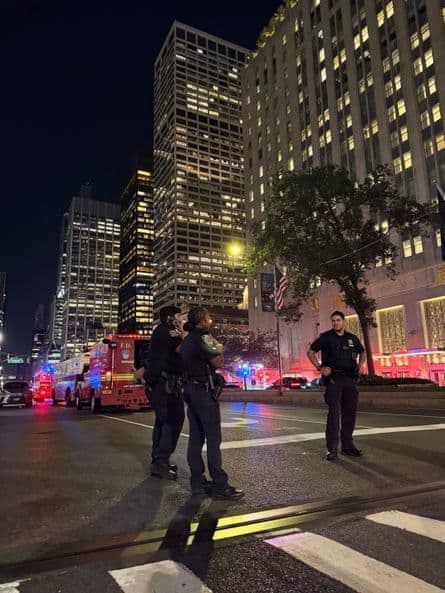 Policiers et véhicules d'urgence devant des gratte-ciel de Manhattan la nuit, suite à une alerte de sécurité.