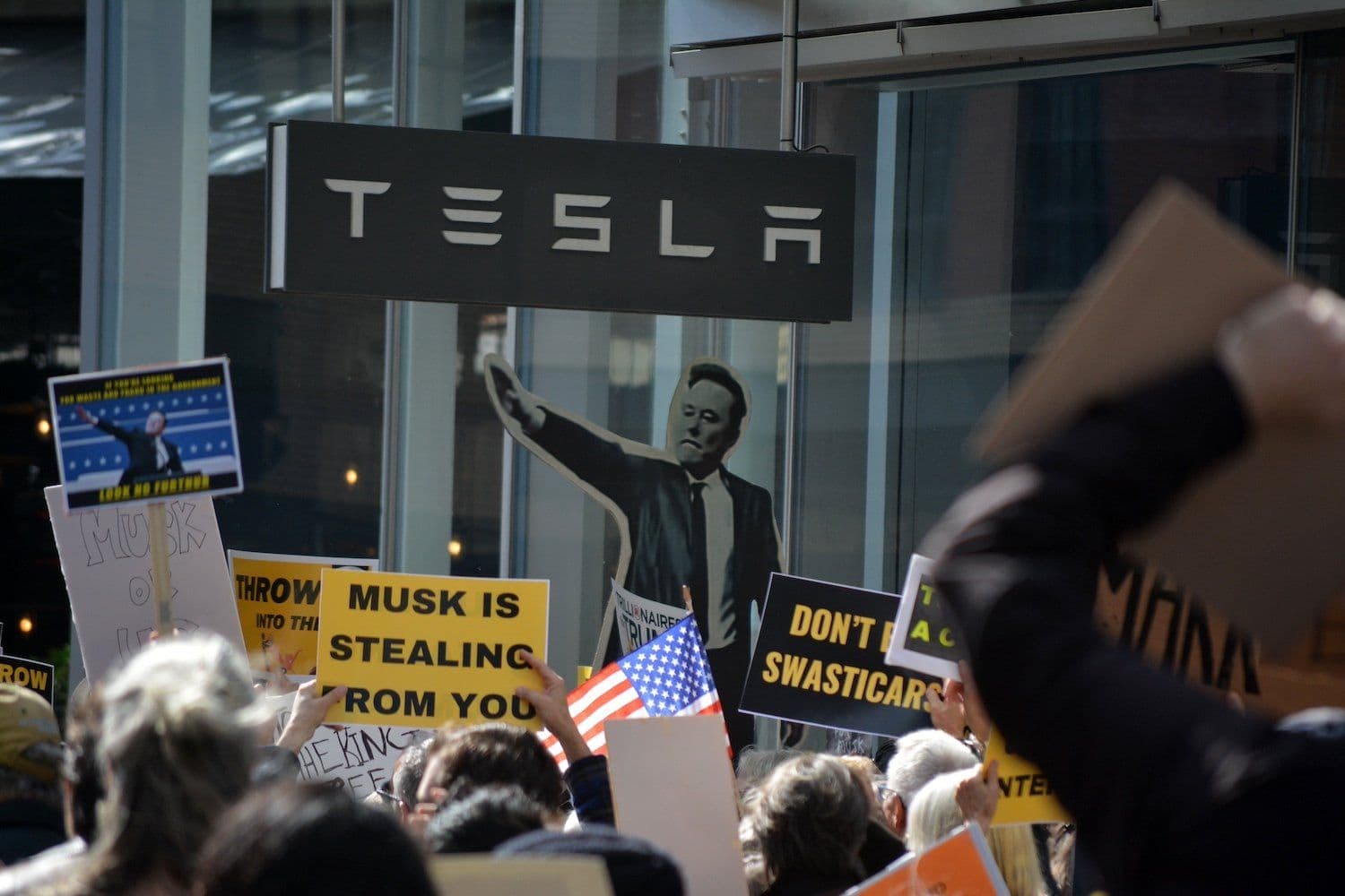 Protestors demonstrating against Elon Musk, reflecting the ethical and regulatory challenges posed by Grok's AI.