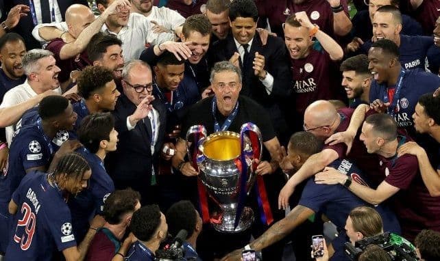 PSG coach Luis Enrique celebrating with players and the Champions League trophy, symbolizing the club's high ambitions and dynamic state.