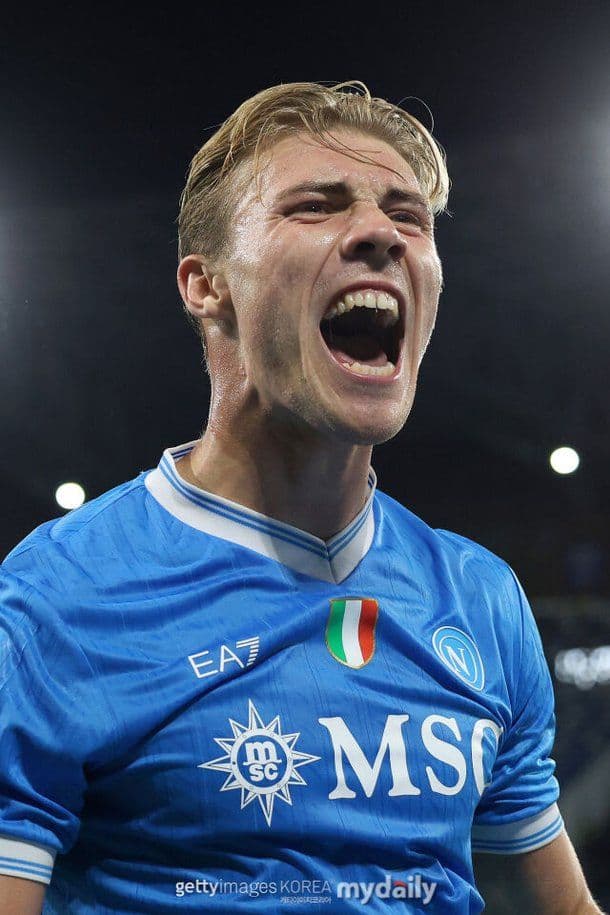 Rasmus Højlund in his Napoli kit celebrating a goal with an intense shout on the football pitch.