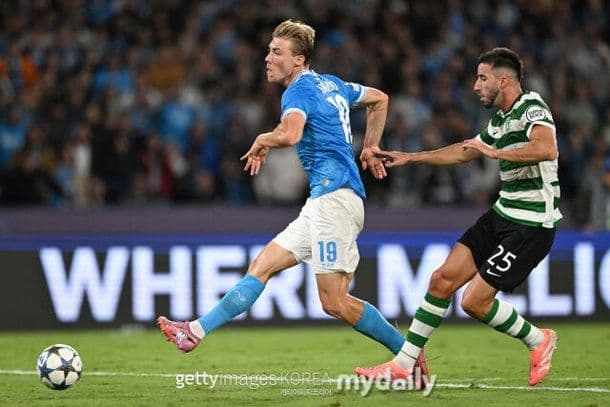Rasmus Højlund in his Napoli kit dribbling the ball past a Sporting Lisbon defender during a Champions League match.