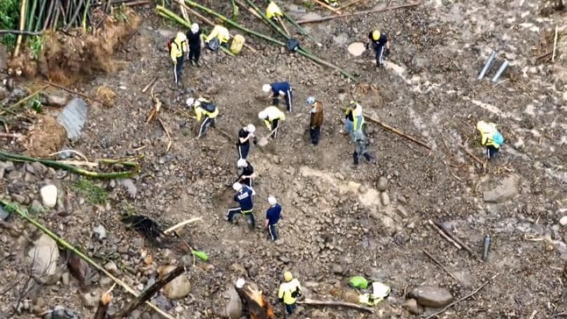 Rescue workers clearing a landslide caused by extreme heavy rainfall in a mountainous area of Taiwan, illustrating the severe impact of recent weather events.