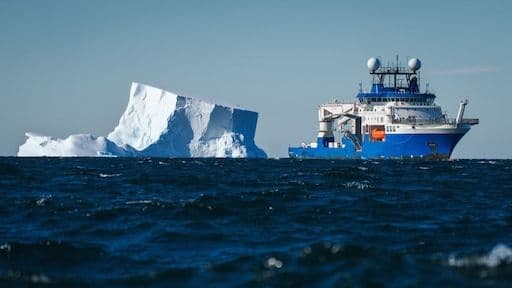 Research vessel exploring vast ocean with large iceberg, symbolizing scientific discovery of new species and hidden ecosystems.