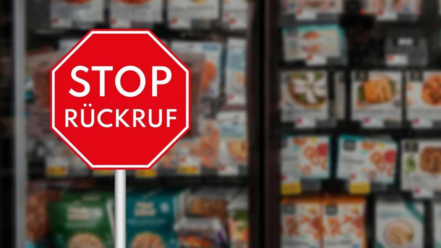 Rotes Stoppschild mit der Aufschrift 'STOP RÜCKRUF' vor unscharfen Supermarktregalen, symbolisiert Lebensmittelrückrufe und Gefahren durch kontaminierte Produkte.