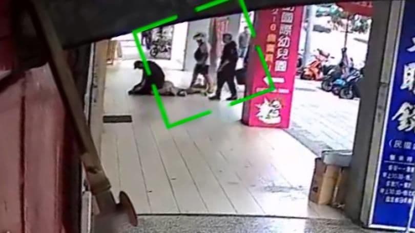 Scène de rue floue avec des personnes et un cadre vert, évoquant un incident ou une surveillance suite à un scandale.