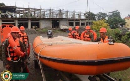 Soldats et secouristes philippins en gilets de sauvetage près d'un bateau de sauvetage, symbolisant la préparation et les efforts de secours face aux intempéries.