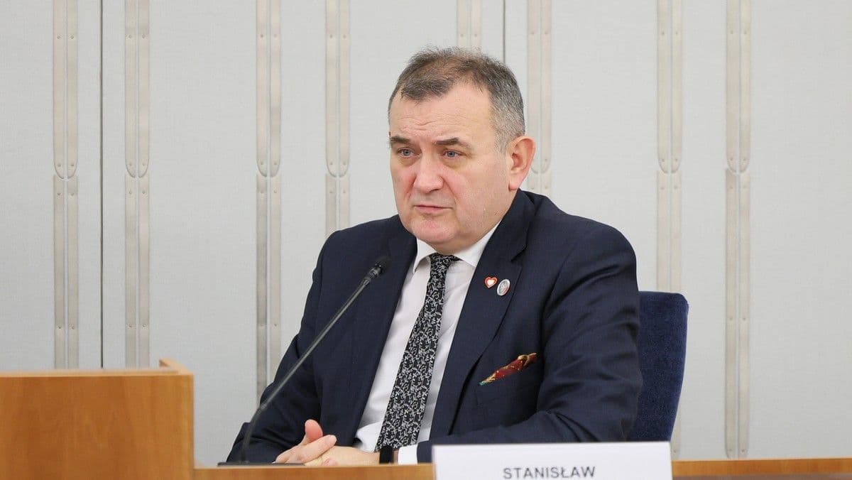Stanisław Gawłowski, sénateur polonais, en costume sombre, assis à une table avec un microphone, lors de son procès.