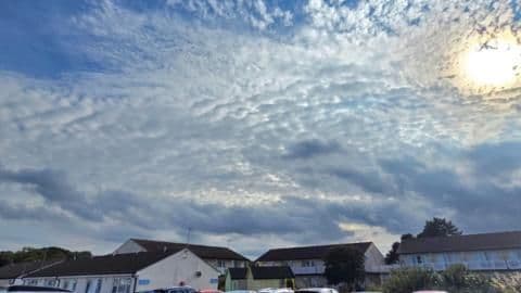 Sunlight breaking through clouds over a row of UK houses, highlighting the need for homes to be adapted for hotter summers.