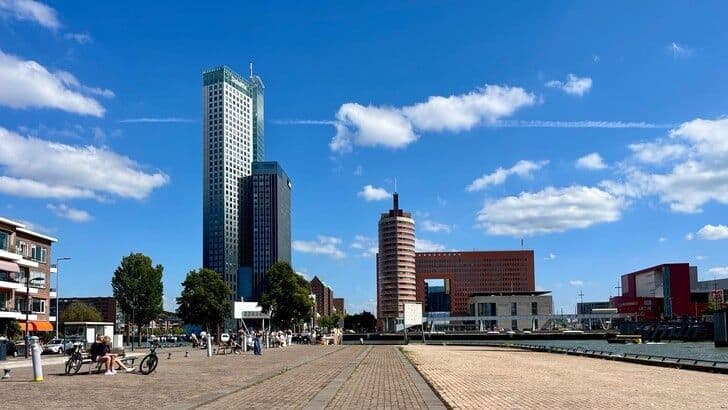 Sunny summer day in Rotterdam with modern city buildings and people, illustrating the local heat in urban areas.