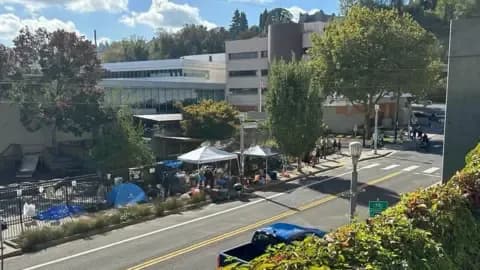 The Portland ICE facility stands next to an abandoned middle school, with tents and protesters gathered outside, illustrating the institutional 'ice' and societal divides.