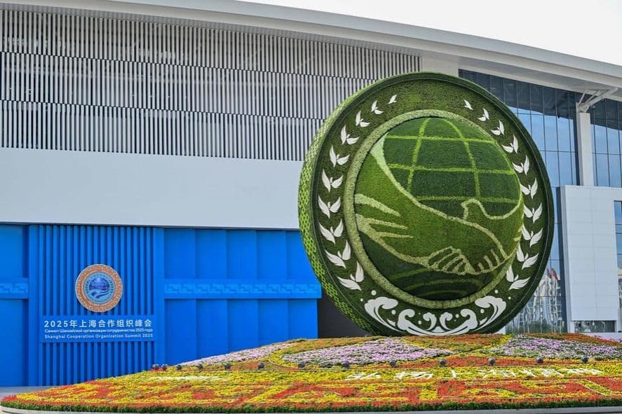 The Shanghai Cooperation Organization (SCO) logo sculpture outside a modern convention center, representing the organization's economic ambition at its summits.