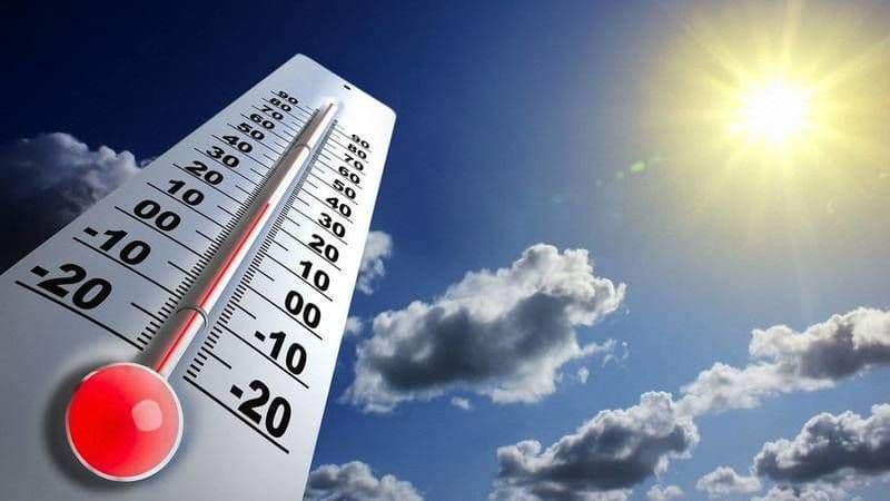 Thermomètre indiquant des températures élevées sous un soleil éclatant et un ciel bleu, symbolisant la météo tunisienne et le Shahili.