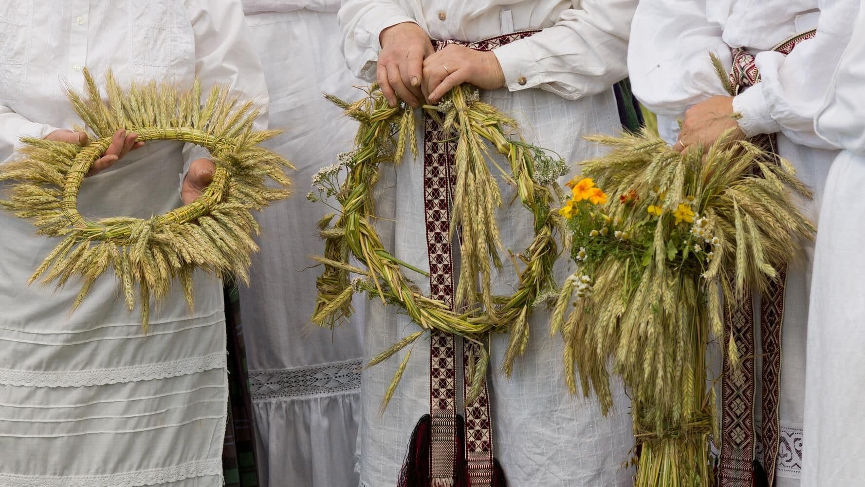Tradicinės lietuviškos šventės dalyviai laiko rugių vainikus ir pėdus, simbolizuojančius derlių ir Oninės šventę.