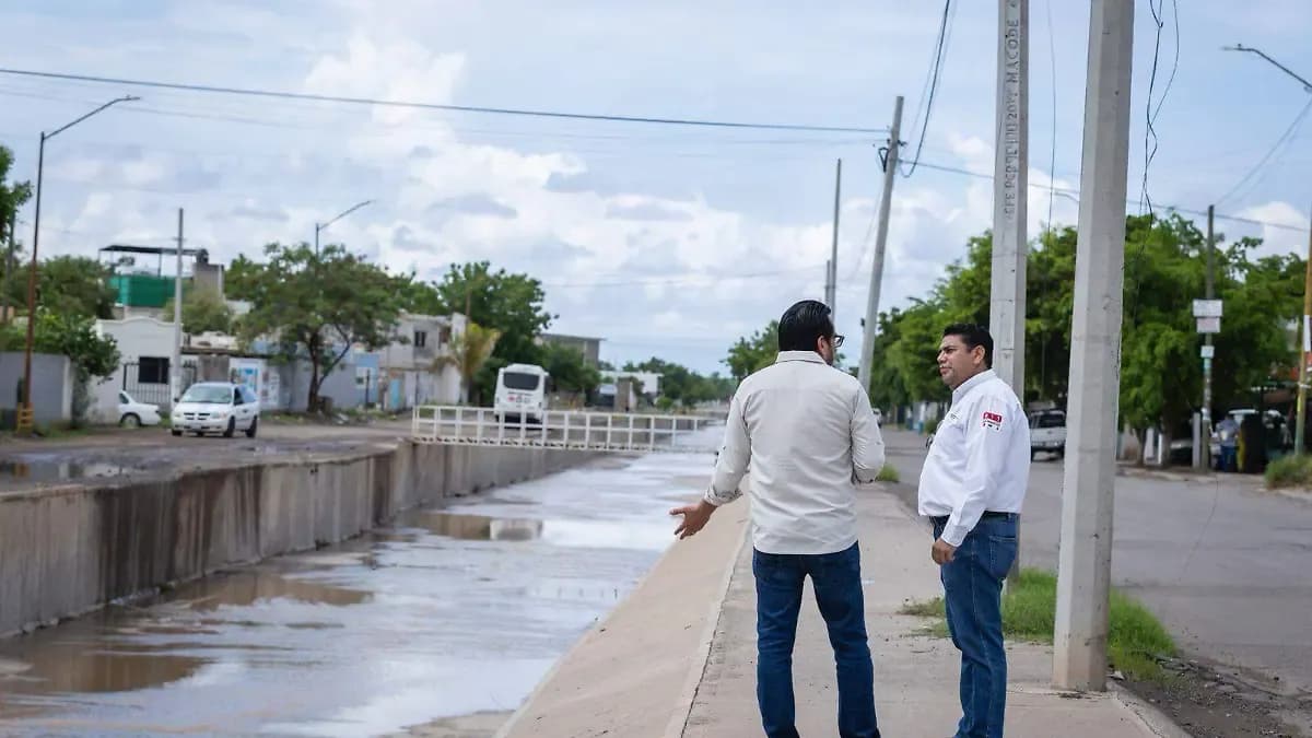 Two men inspecting a concrete drainage canal in Culiacán, highlighting urban adaptation to heavy rains.