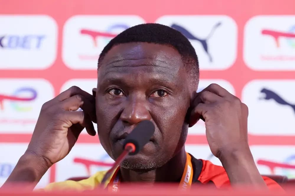 Uganda's coach Morley Byekwaso at a press conference, discussing tactical strategy.