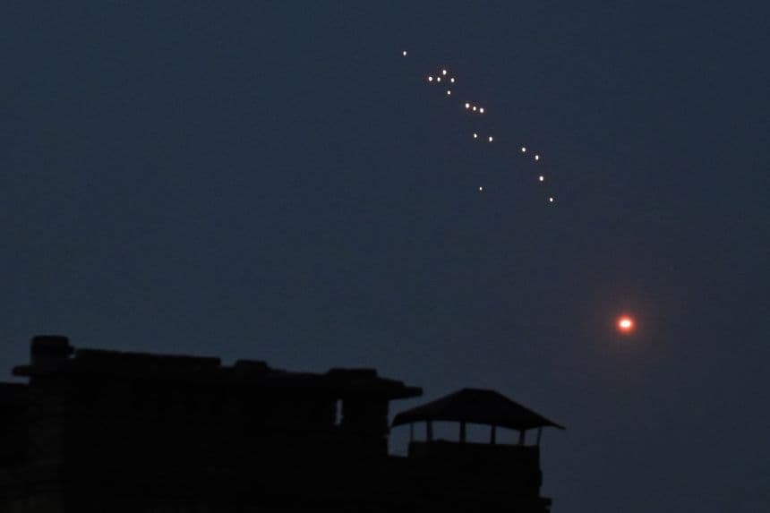 Ukrainian air defense system firing tracer rounds at Russian drones in a dark sky, illustrating the threat of aerial incursions and defense.