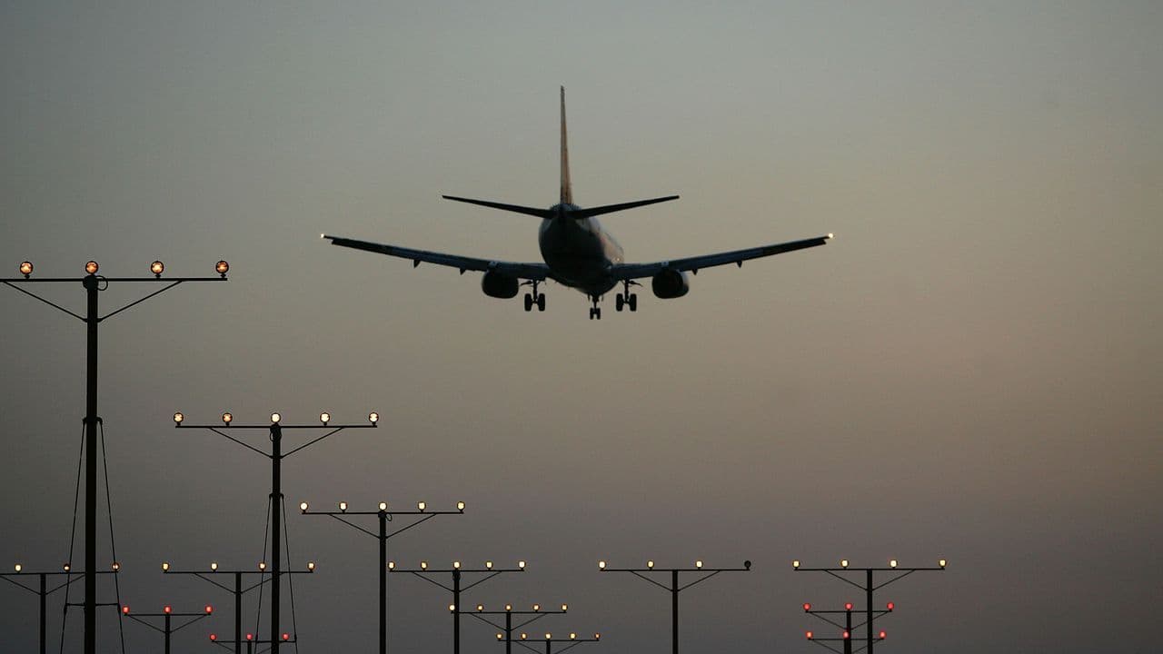 Un avion en approche ou au décollage, avec des lumières de piste en premier plan, symbolisant l'impact de la grêle sur le transport aérien.