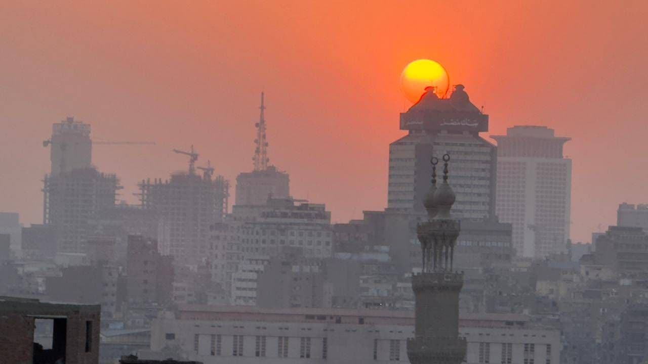 Un ciel rougeoyant au-dessus d'une ville égyptienne, évoquant le dérèglement climatique et l'intensification des phénomènes météorologiques extrêmes.