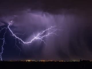 Un éclair illuminant le ciel nocturne au-dessus d'une ville, rappelant les dangers des orages et l'importance des mesures de sécurité.