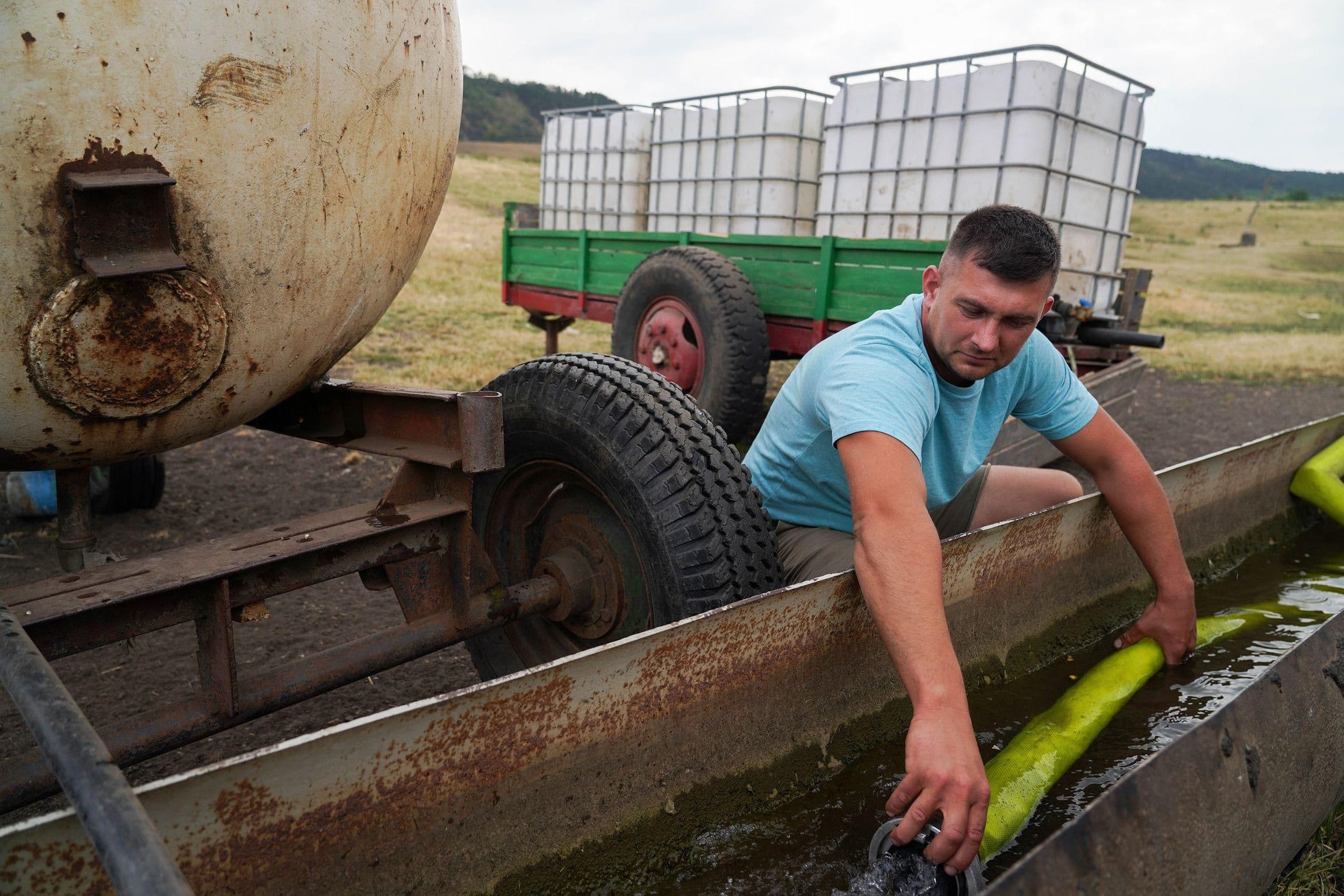 Un fermier de Gănești stocke l'eau livrée par les pompiers, illustrant le fardeau économique et social de la crise de l'eau.