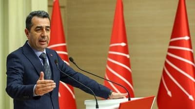 Un homme politique s'exprimant devant des drapeaux du CHP, illustrant l'escalade verbale dans le débat politique turc.