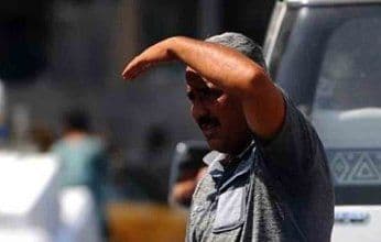 Un homme protégeant ses yeux du soleil intense, illustrant la chaleur ressentie et les défis des températures extrêmes en Égypte.