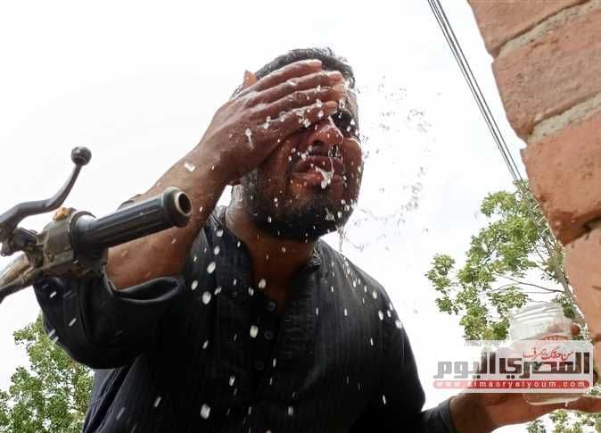 Un homme se rafraîchissant avec de l'eau pour combattre l'humidité étouffante et la chaleur.