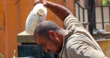 Un homme se versant de l'eau sur la tête pour se rafraîchir pendant une vague de chaleur en Égypte.