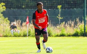 Un joueur de football dribblant le ballon sur le terrain.