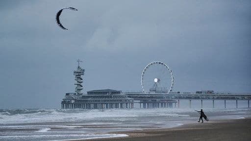 Un kitesurfeur sur une plage agitée sous un ciel orageux, illustrant les phénomènes climatiques extrêmes au Royaume-Uni.