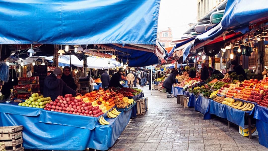 Un marché alimentaire animé avec des étals de fruits et légumes, illustrant les origines et le cœur de métier d'Özel Gıda dans le secteur alimentaire.