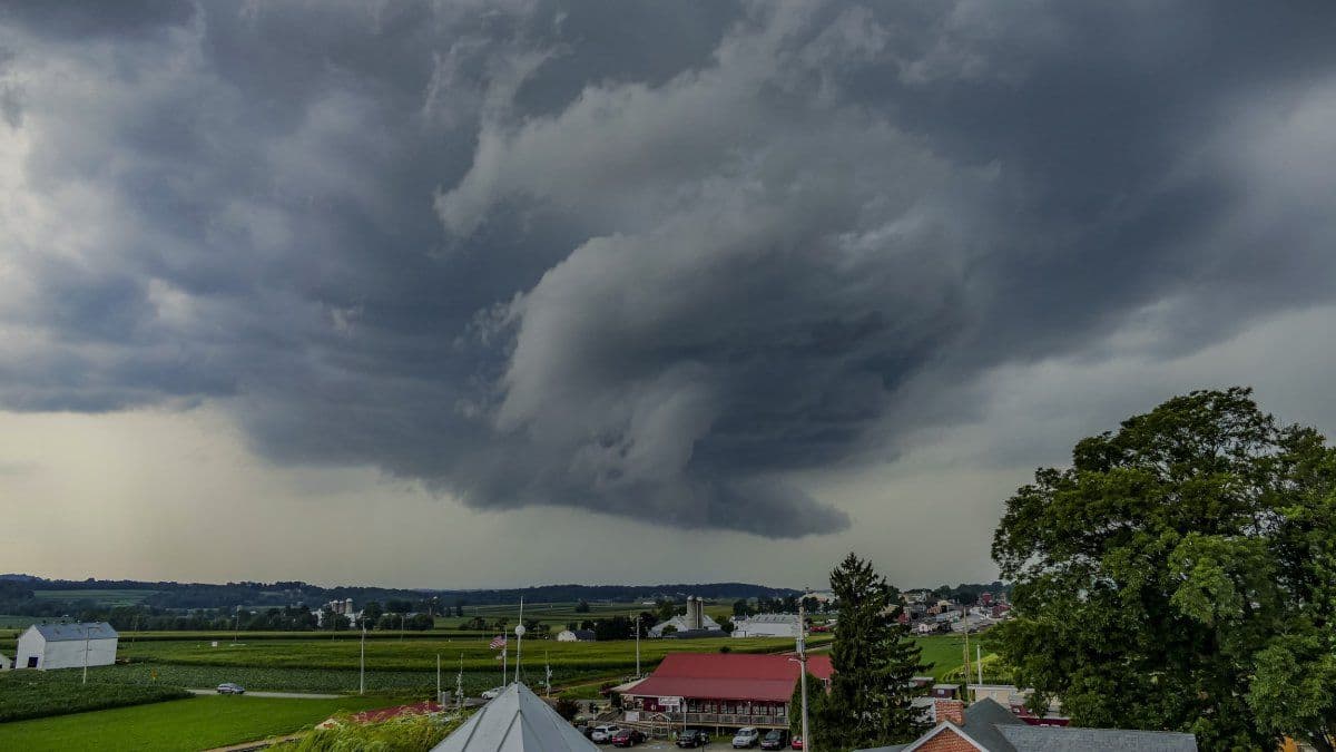 Un orage violent avec des nuages menaçants et tourbillonnants au-dessus d'un paysage rural.