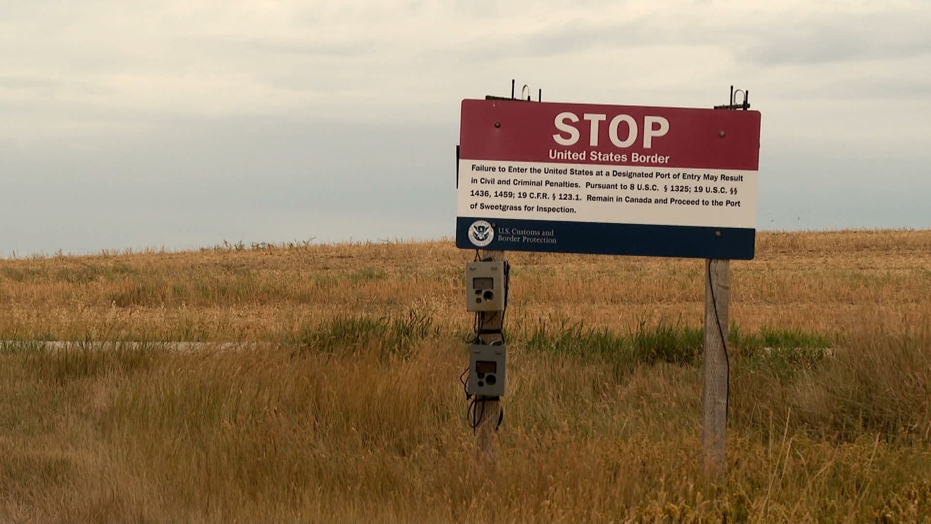 Un panneau 'STOP United States Border' dans un paysage rural, symbolisant les taxes frontalières et la portée des pouvoirs présidentiels en matière de commerce.