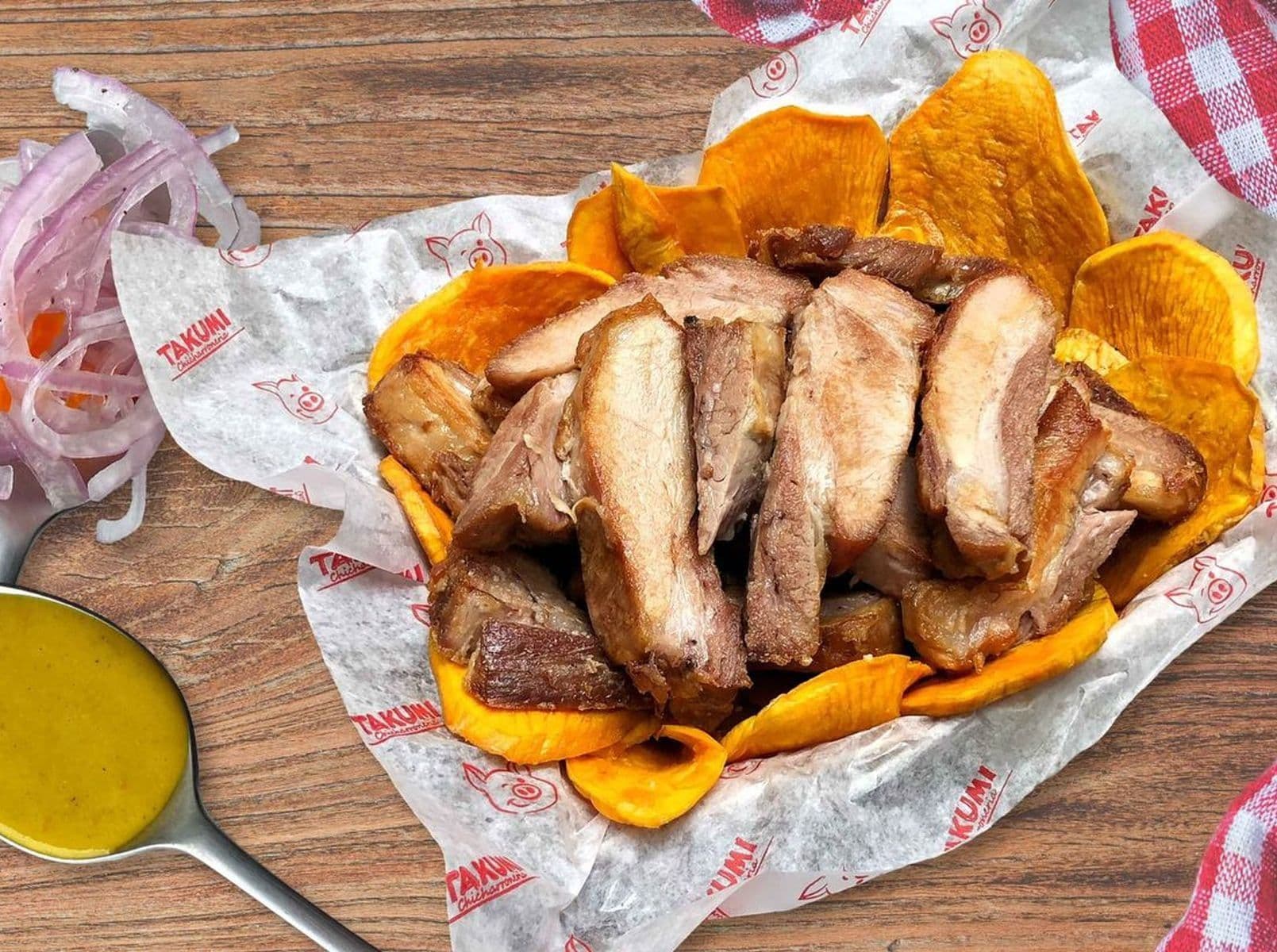 Un plat de chicharrón péruvien avec des patates douces frites et des oignons rouges, représentant la richesse des petits-déjeuners sud-américains mis en lumière.