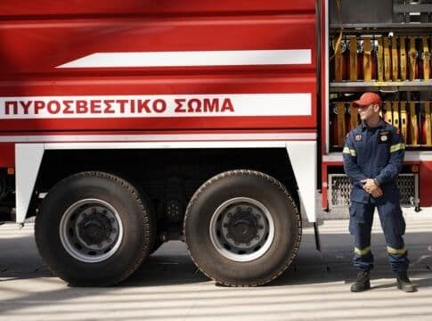 Un pompier grec devant un camion de pompiers, symbolisant l'adaptation et la résilience face aux défis climatiques.