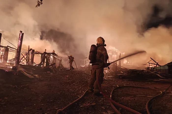 Un pompier équipé combat l'incendie dévastateur au milieu de la fumée et des débris de l'Ocupação Resistência e Luta à Campo Bom.