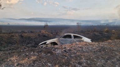 Un véhicule calciné au milieu d'un paysage dévasté par l'incendie, symbolisant l'héritage destructeur des flammes à Lesovo.