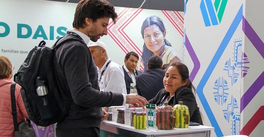 Un visiteur interagissant avec un exposant à un stand d'Expoalimentaria, symbolisant les échanges commerciaux internationaux.