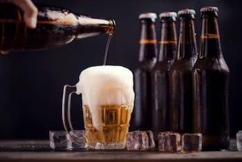 Une bière est versée d'une bouteille dans un verre, représentant la précision technique et la qualité des ingrédients du brassage.