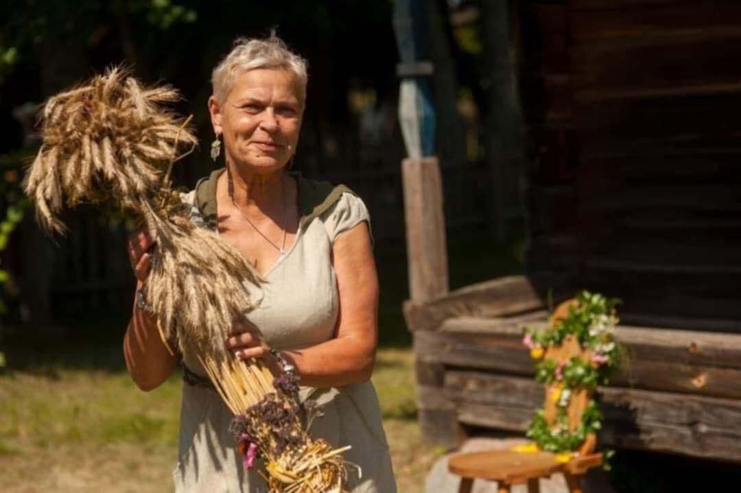 Une femme lituanienne tenant une gerbe de seigle, symbolisant la récolte et l'abondance liée à Sainte Anne.
