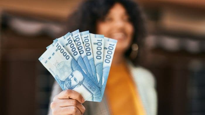 Une femme souriante tenant des billets de 10 000 pesos chiliens, symbolisant l'aide financière de Sence.