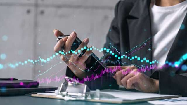 Une personne utilisant un smartphone avec des graphiques financiers superposés, symbolisant la technologie et la performance boursière de JianDian.