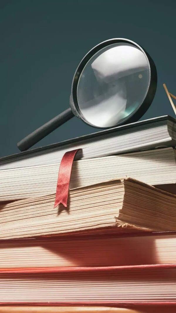 Une pile de livres avec une loupe, symbolisant la recherche de connaissance et la compréhension du monde.