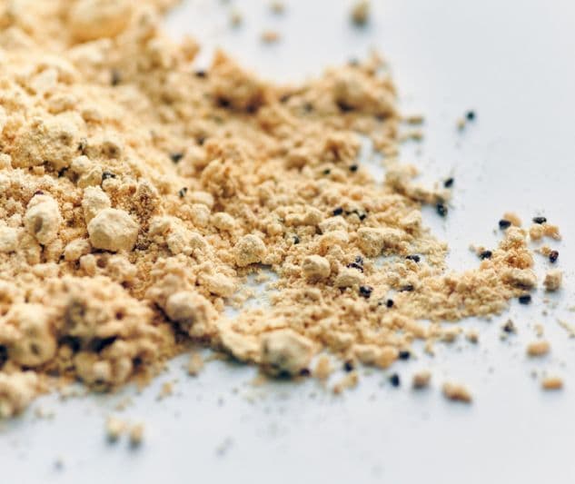 Une pile de poudre jaune avec de petits points noirs, potentiellement des criquets transformés en produit, symbolisant l'ingéniosité humaine.