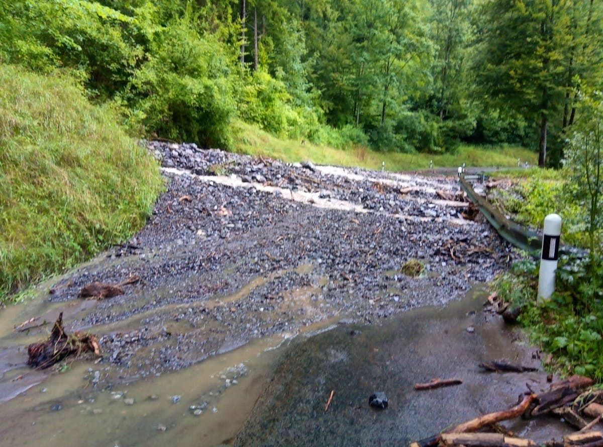 Une route de montagne recouverte par une coulée de boue et de roches suite à un glissement de terrain.
