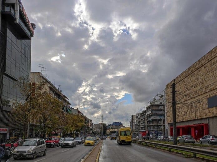 Une rue grecque avec des voitures sous un ciel lourdement nuageux, annonçant un orage.
