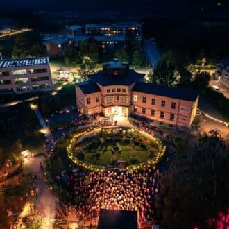 Une vue aérienne nocturne d'un grand bâtiment animé par une foule, illustrant l'impact économique et social sur les entreprises et la communauté du Mondsee.